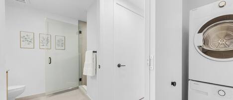 A modern bathroom with a toilet, a glass shower enclosure, and a white door.