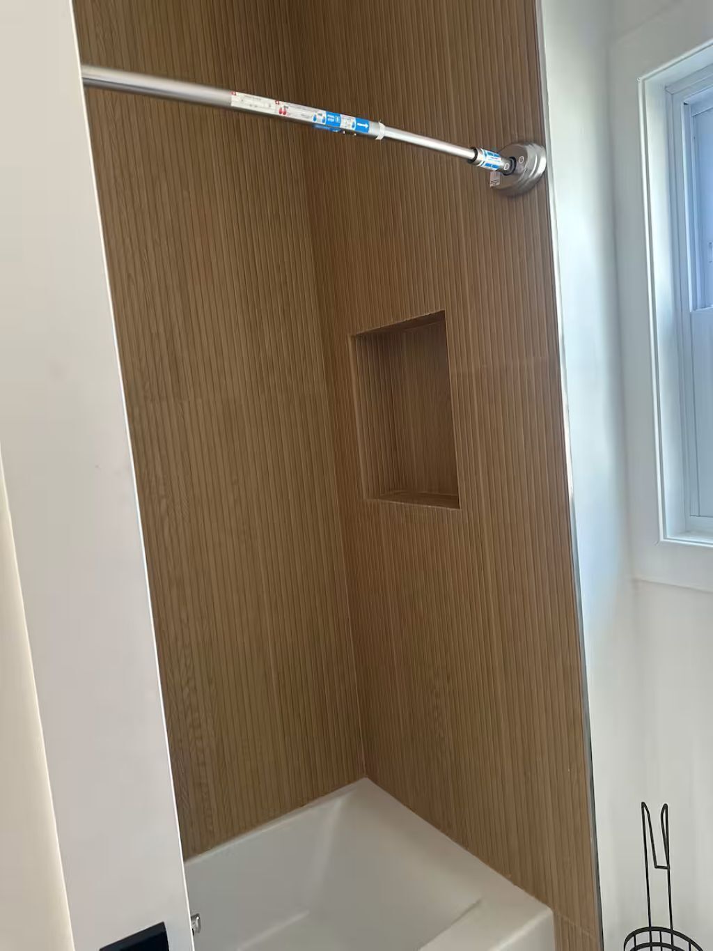 Une salle de bain avec un mur en bois, un espace douche et une fenêtre.