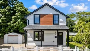 Een tweelaags huis met garage, voortuin en witte hekken.