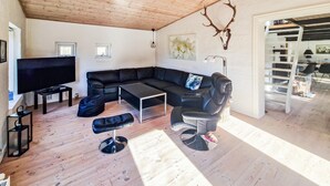 Un salon moderne avec un canapé d’angle, un téléviseur et un plafond en bois.