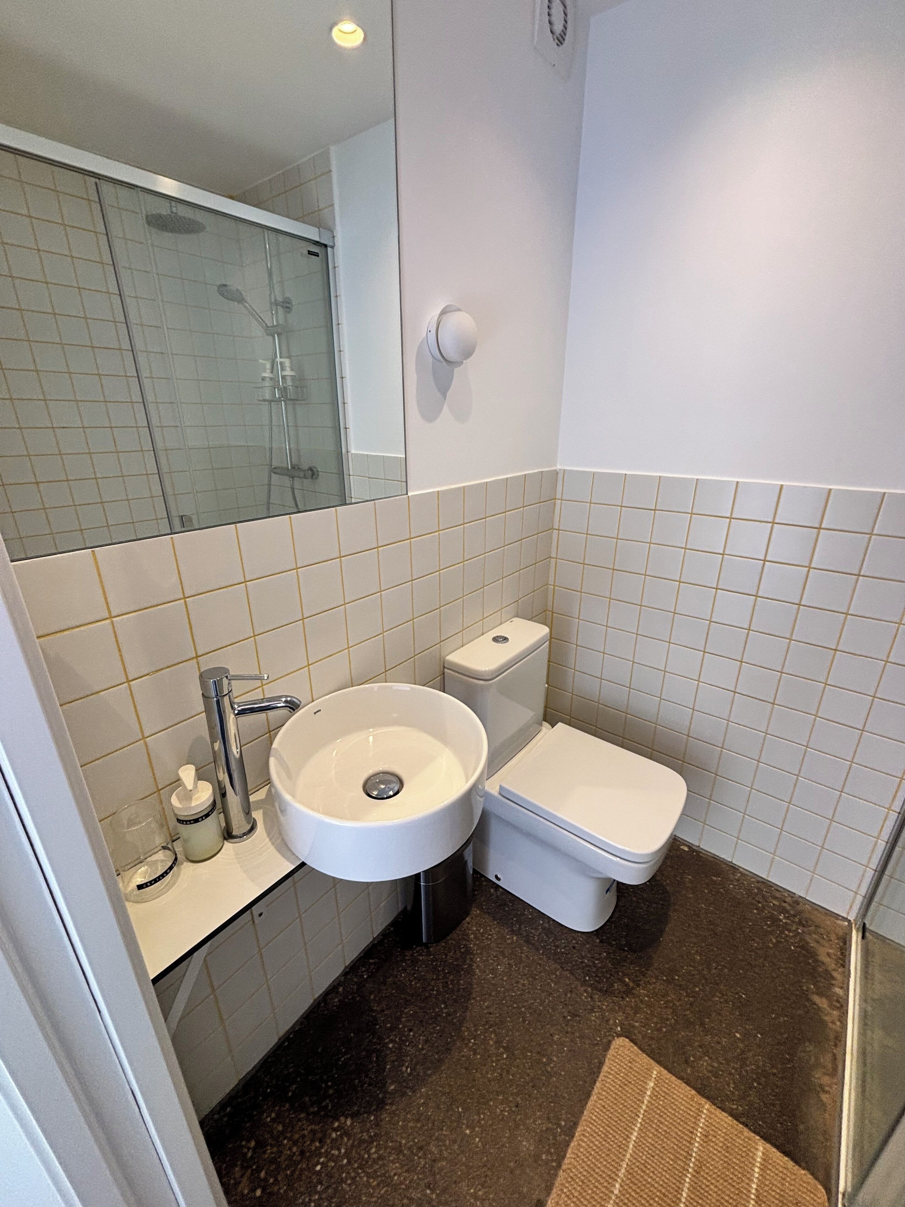 A bathroom with a white sink, toilet, and a glass shower enclosure.