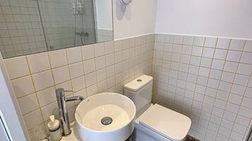 A bathroom with a white sink, toilet, and a glass shower enclosure.
