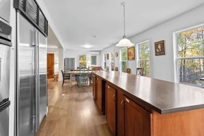 A kitchen with a wooden island, stainless steel appliances, and a dining area with chairs.