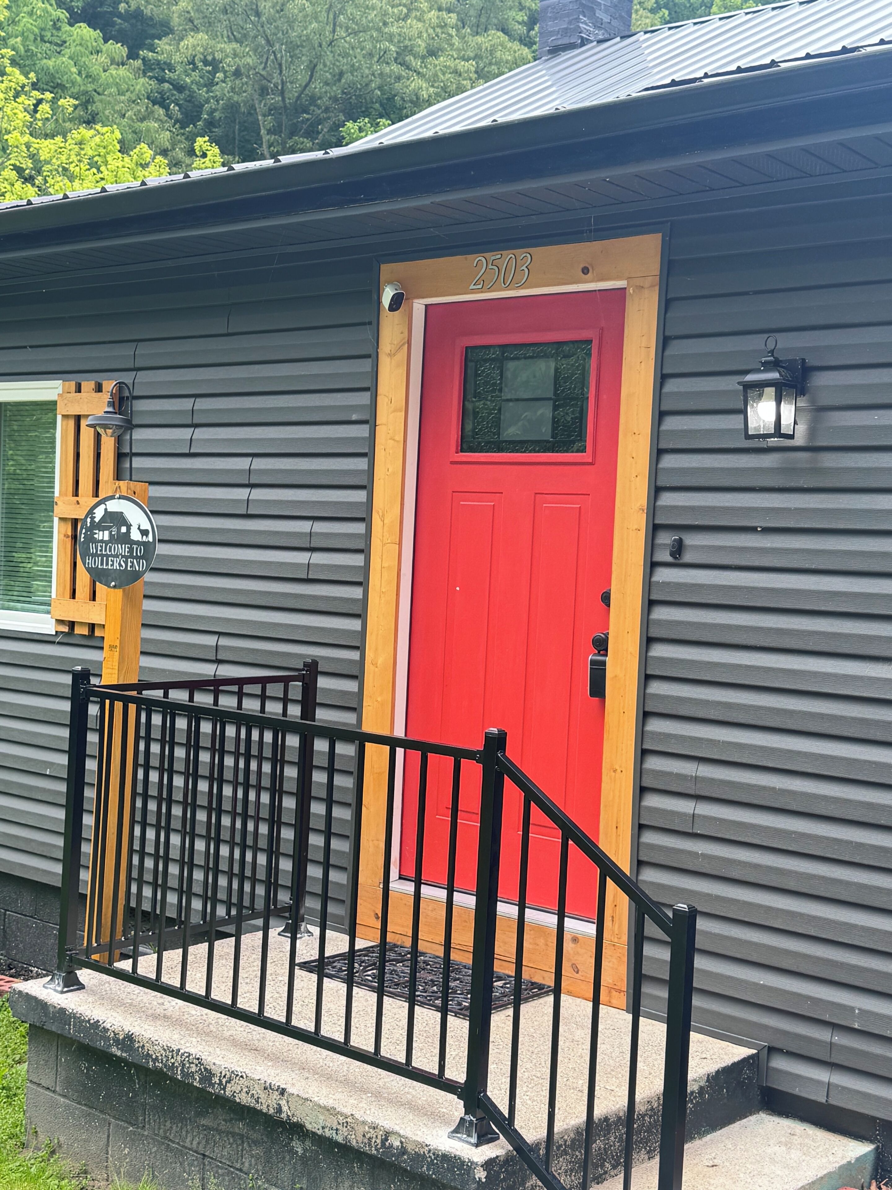 A building with a red door, a mailbox, and a welcome sign.
