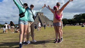 Three people standing in a grassy area with a pyramid in the background. - Early access tour to Chichen Itza, Cenote Hubiku and Valladolid. (cancun)