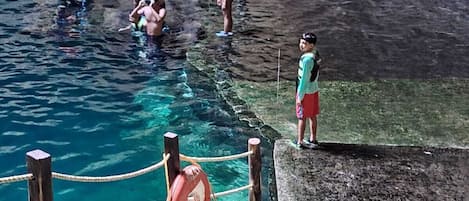 A swimming pool area with stone steps and a rope safety barrier.