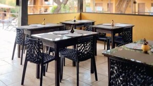 En udendørs café med træborde og -stole, store vinduer og et flisegulv.