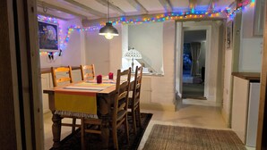 Un coin repas avec une table en bois, des chaises, une lampe et des guirlandes lumineuses colorées.