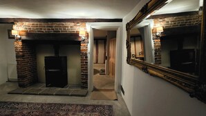 Un couloir avec une cheminée en briques, un grand miroir et un sol recouvert de moquette.