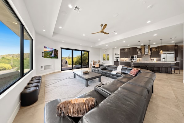 A spacious living area with a large sofa, a coffee table, and a view of the outdoors.