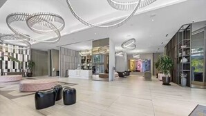Un vestíbulo espacioso con iluminación moderna, una zona de estar central y un mostrador de recepción.