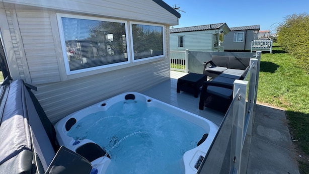 Un bain à remous sur une terrasse, avec vue sur une maison et une clôture.