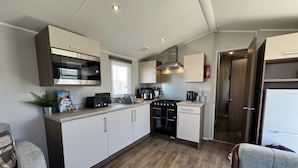 Une petite cuisine équipée d’un four à micro-ondes, d’une cuisinière et d’un évier.