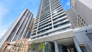 Un edificio moderno de gran altura con una entrada destacada, ventanas amplias y techo plano.