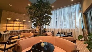 A modern interior with a central seating area, a large tree, and a skylight. - 2411 Brand New 1BR - Rooftop Pool, Coworking, Gym, Saun (Miami)