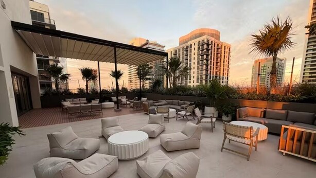 A rooftop patio with outdoor seating, palm trees, and high-rise buildings in the background. - 2411 Brand New 1BR - Rooftop Pool, Coworking, Gym, Saun (Miami)