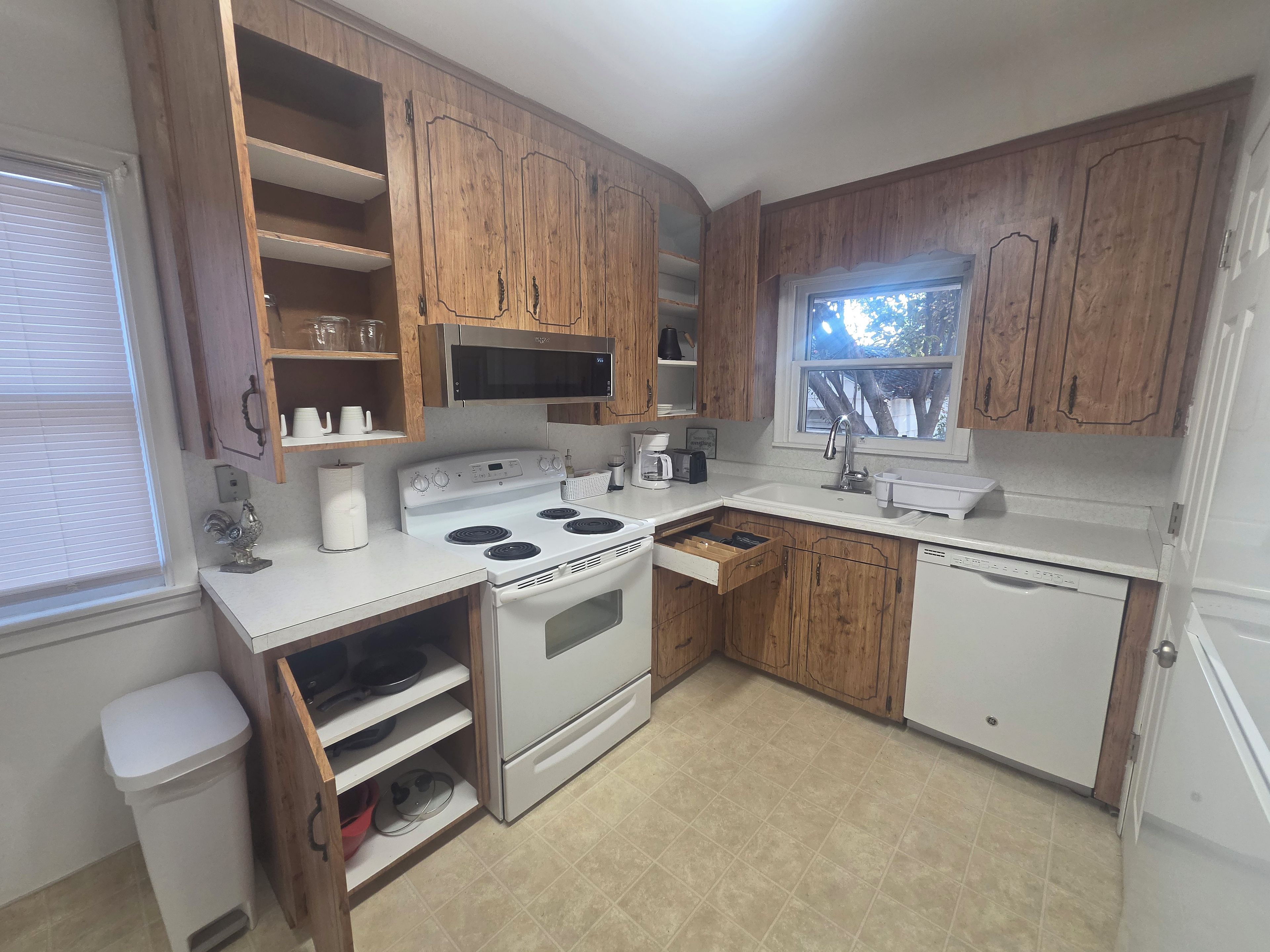 A kitchen with wooden cabinets, a white stove, and a sink.