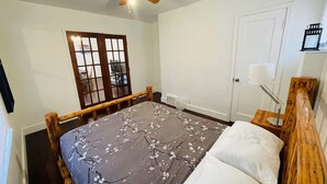 Un dormitorio con cama, ventilador de techo, ventana con vistas y puerta.