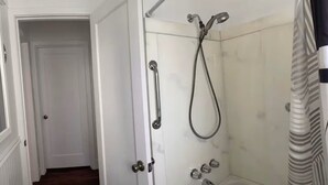 Un baño con ducha, una puerta y una cortina estampada.