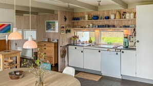 Una cocina moderna con armarios de madera, horno empotrado y ventana con vistas a un jardín.