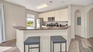 Una cocina moderna con una isla central, taburetes de bar y electrodomésticos integrados.