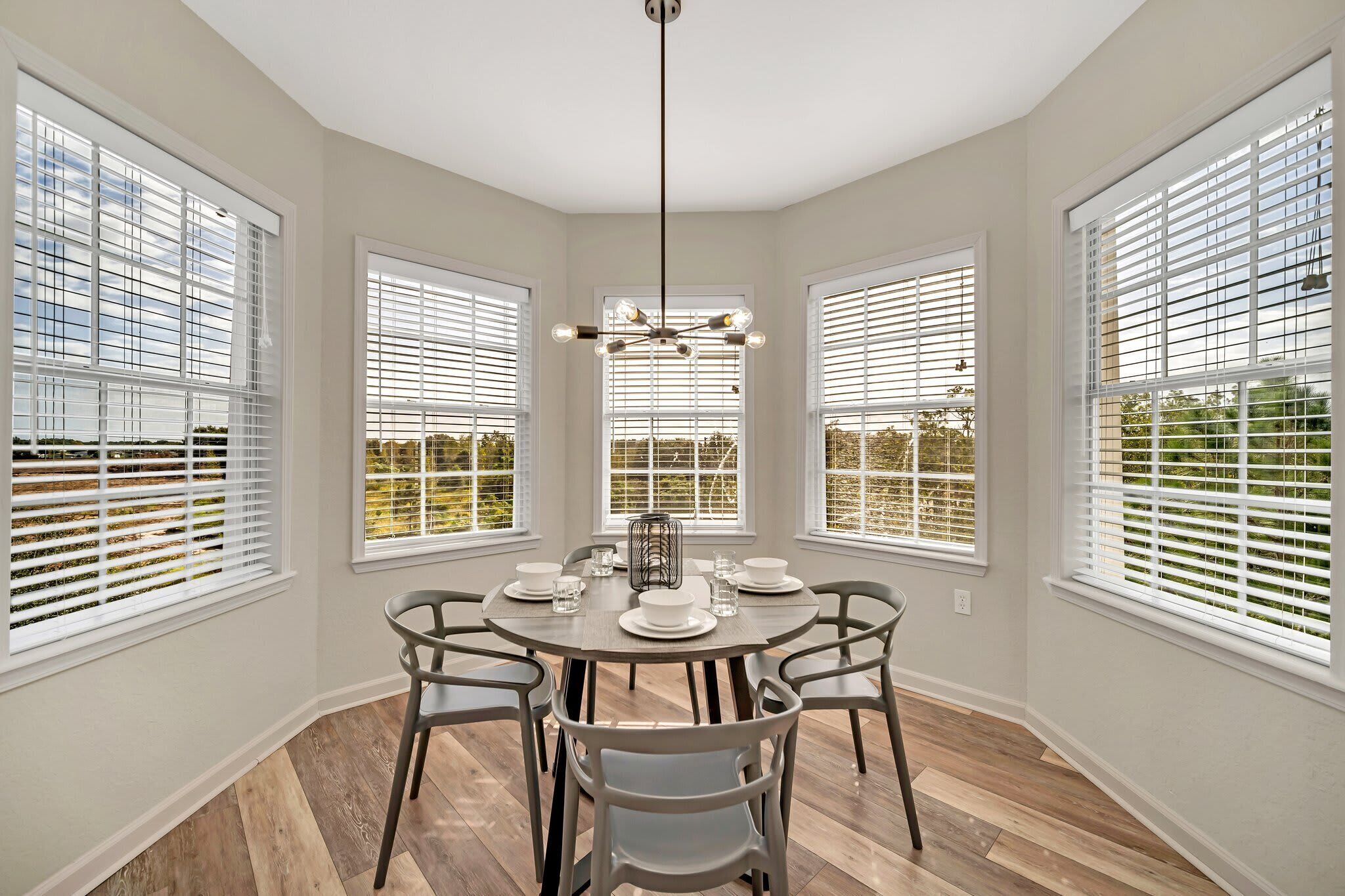 A dining area with a round table, chairs, and a chandelier.