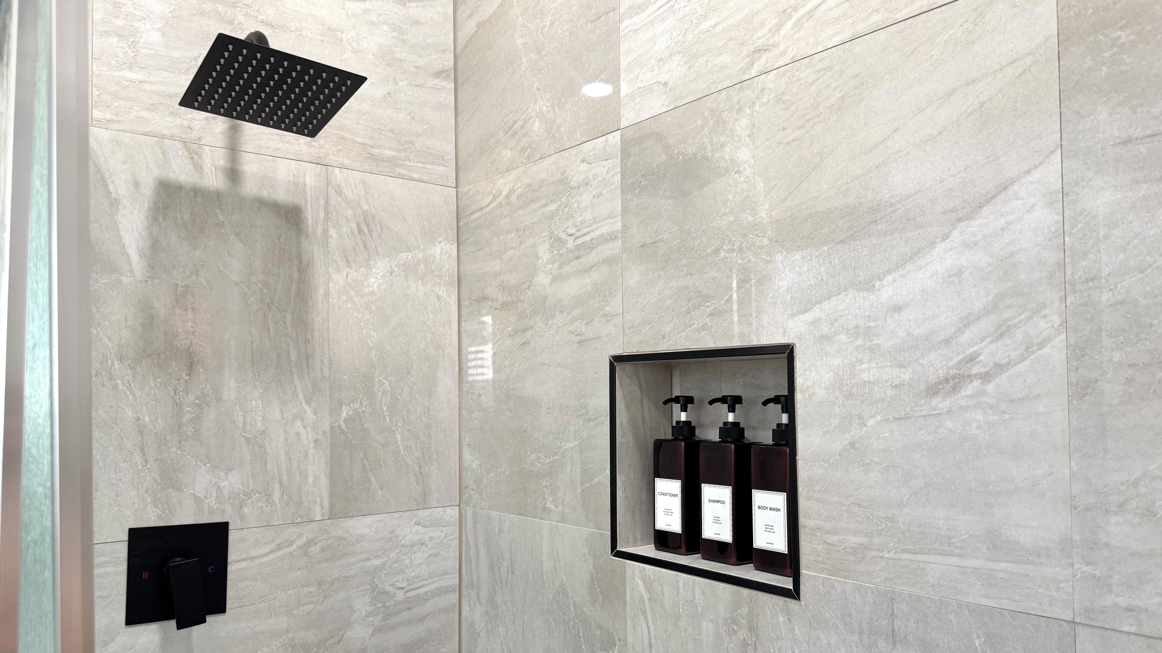 Un baño moderno con ducha, dispensador de jabón integrado y panel de control.