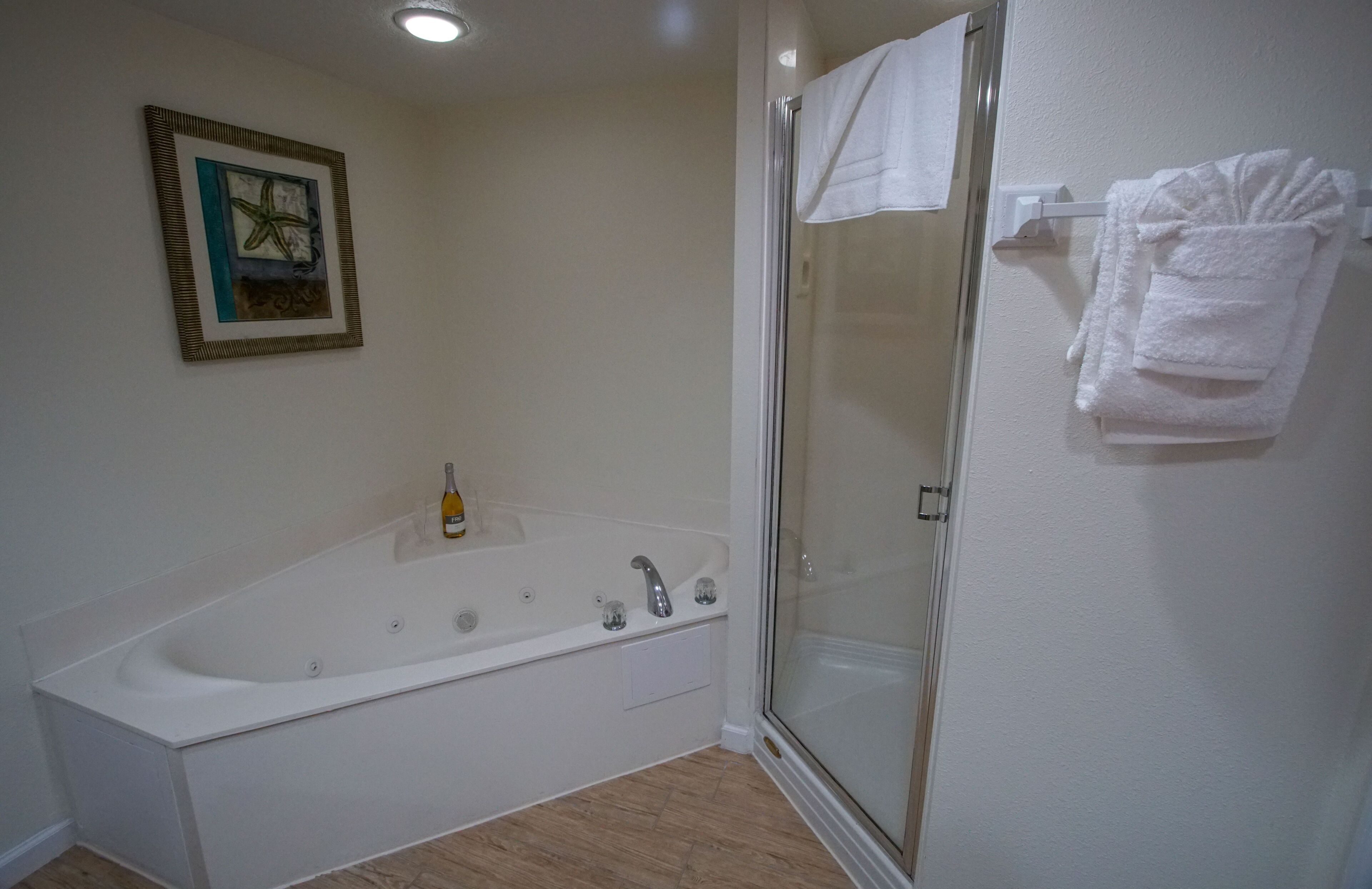 Une salle de bain avec une baignoire, une cabine de douche en verre, un porte-serviettes et une œuvre d’art encadrée au mur.