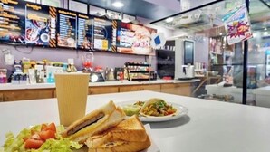 Ein Restaurantinneres mit einer Theke, Speisekarten und einem Sandwich auf einem Teller.