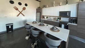 Eine moderne Küche mit einer zentralen Kochinsel, Barhocker, einer Mikrowelle und einem Kühlschrank.