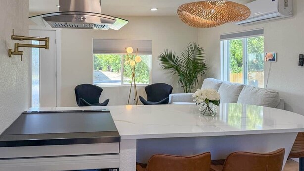 A modern kitchen with a central island, pendant lighting, and a large window.
