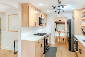 Une cuisine moderne avec des meubles en bois, un four à micro-ondes, une cuisinière et un coin repas comprenant une table et des chaises.