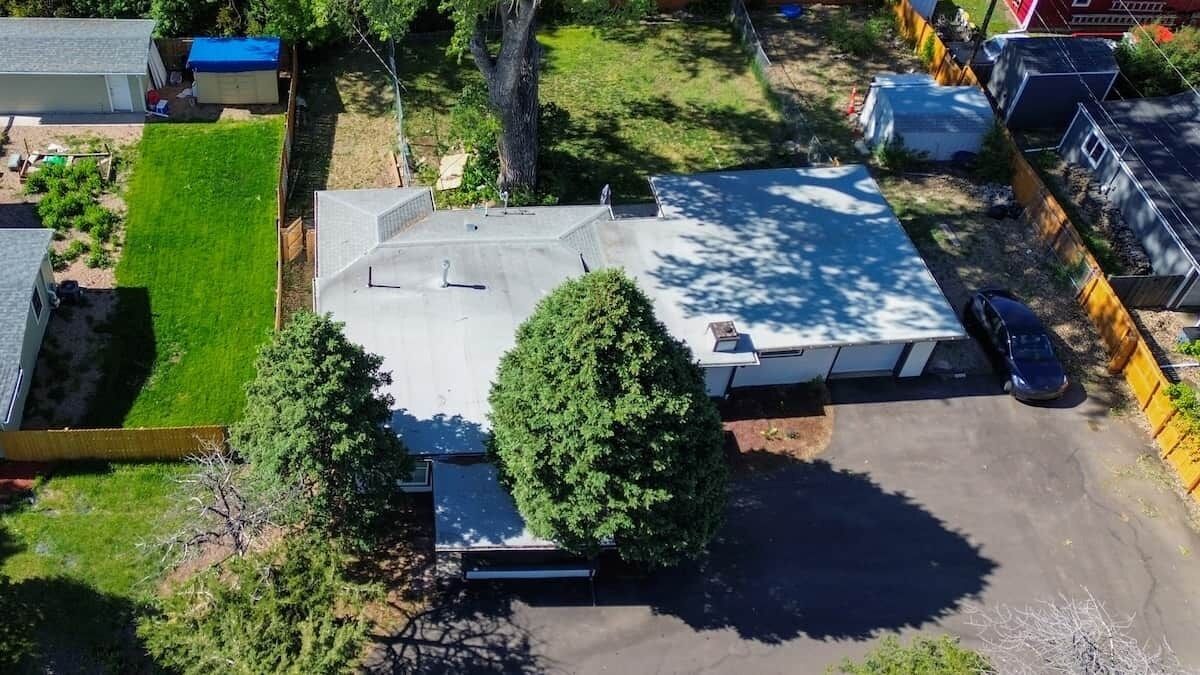 Una propiedad residencial con patio cercado, terraza cubierta y un coche estacionado en la entrada.