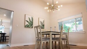 Ein Essbereich mit Tisch und Stühlen, einer Chandelier und zwei gerahmten Bildern an der Wand.