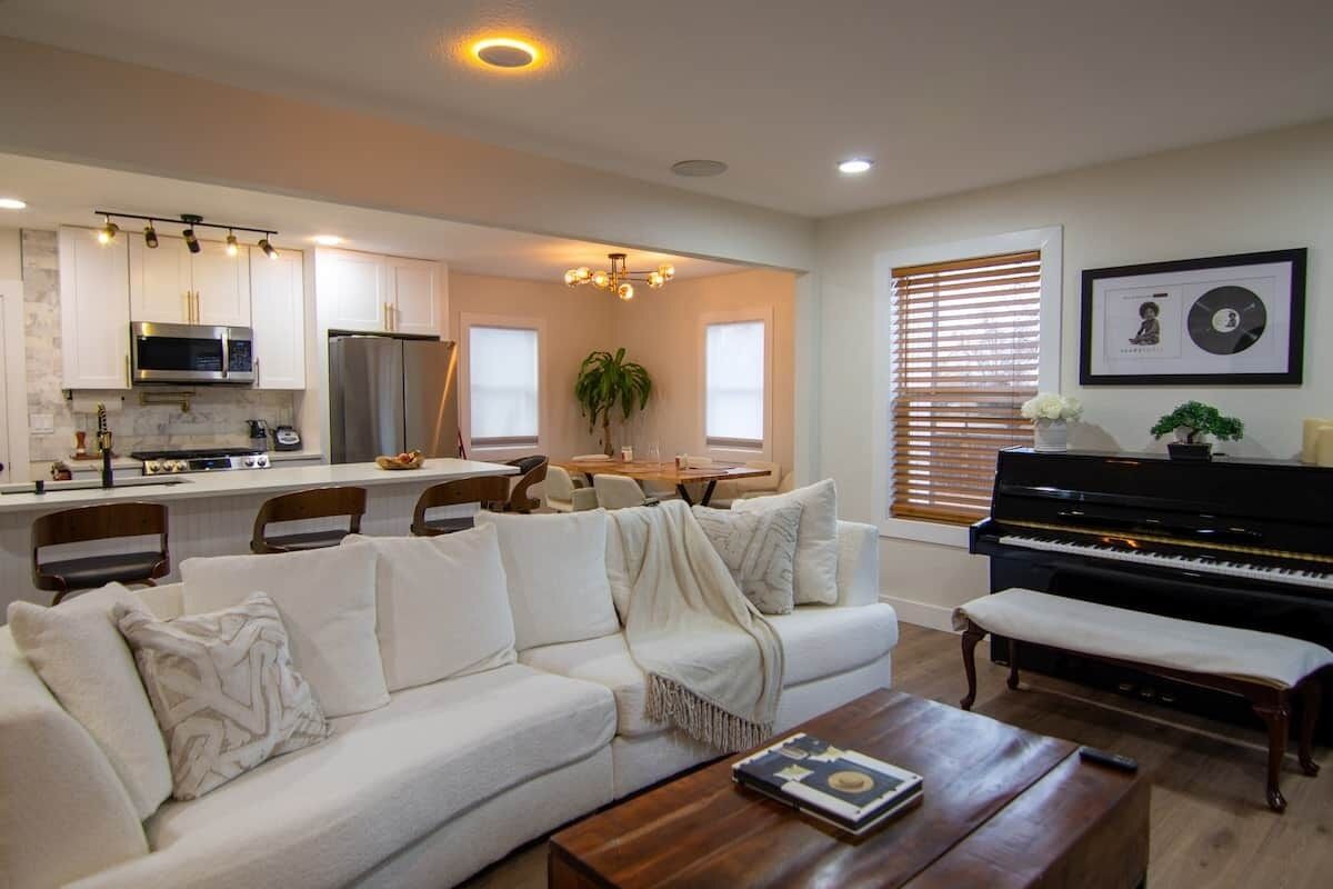 A modern living room with a sofa, coffee table, and a piano.