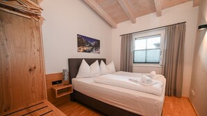 A bedroom with a wooden bed, a nightstand, a window with curtains, and a picture on the wall. - Ski & Golf Suite 25: balcony, Maiskogel View (Kaprun)