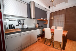 Eine moderne Küche mit Geschirrspüler, Edelstahl-Dunstabzugshaube und einem Essbereich mit Holztisch und Stühlen.