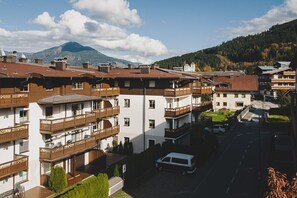 Ein mehrstöckiges Gebäude mit Balkonen, einem Parkplatz und einem Berg im Hintergrund.
