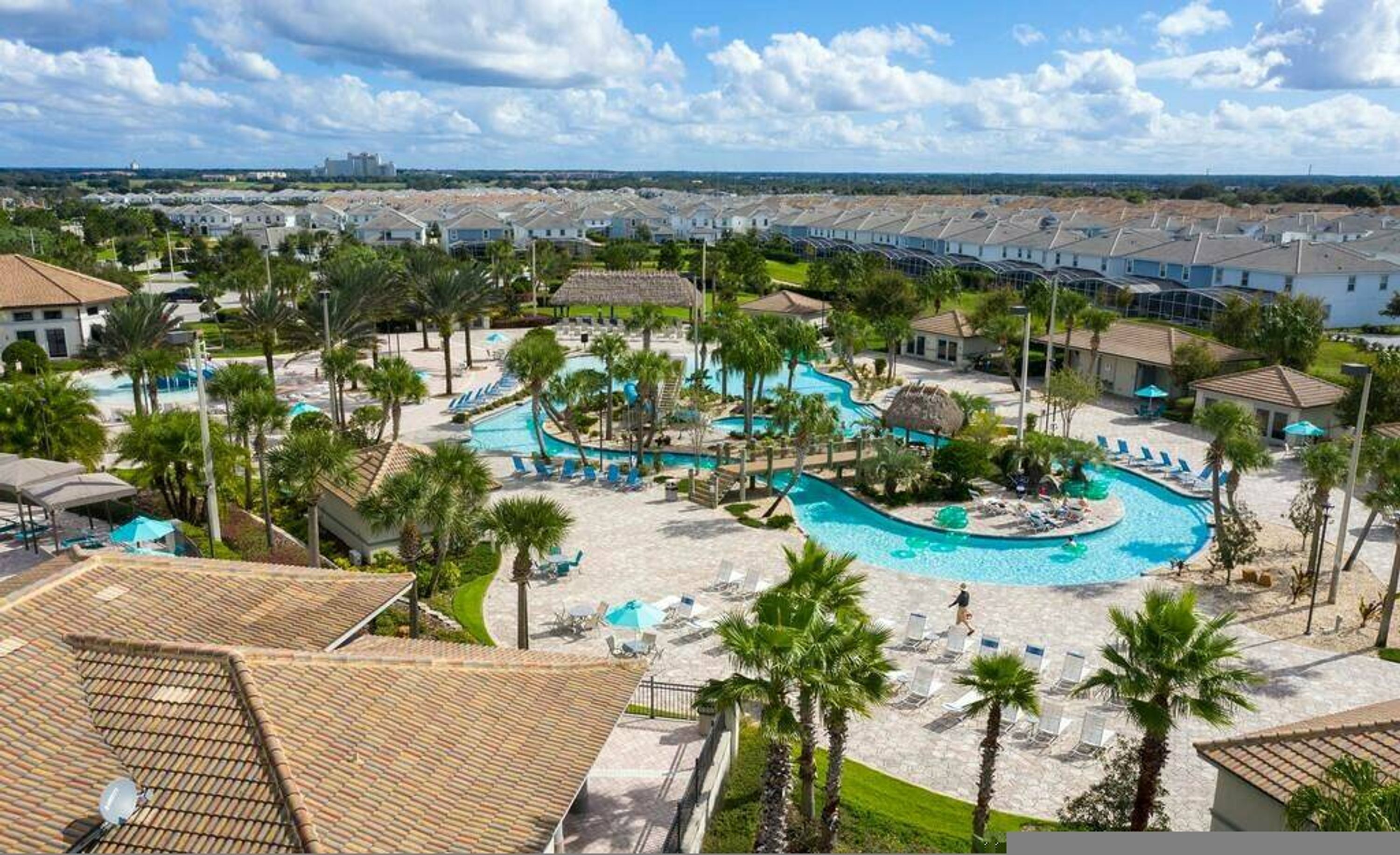 A resort with multiple swimming pools, palm trees, and a view of the surrounding area.