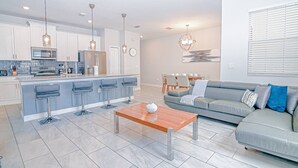 Een moderne keuken met een centraal kookeiland, barstoelen en hanglampen.
