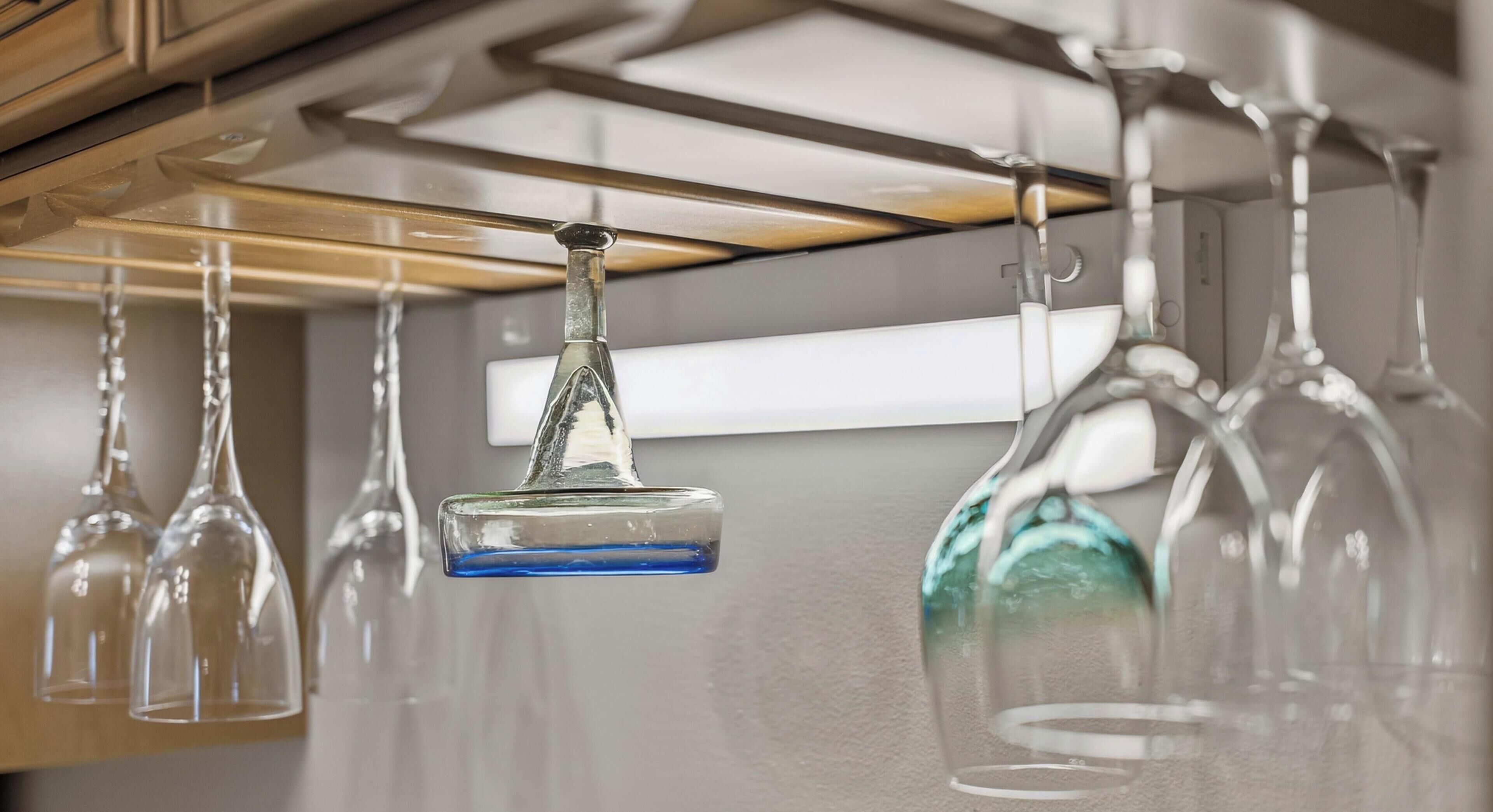 A row of wine glasses hanging from a ceiling, with a single wine glass suspended by a hook.