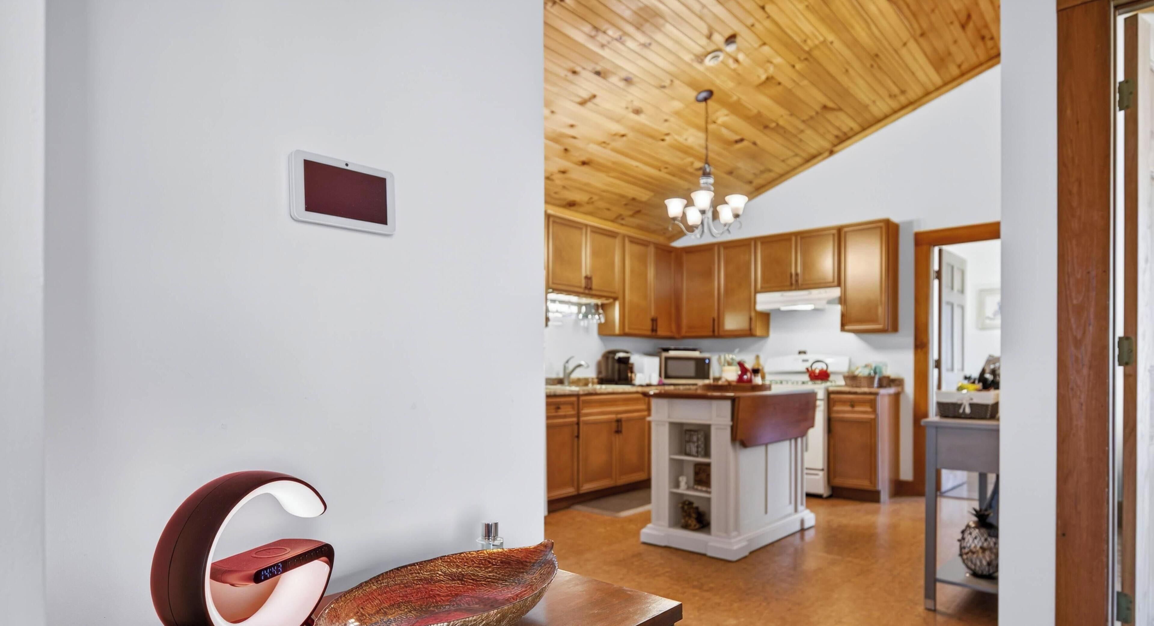 A modern kitchen with wooden cabinets, a central island, and a ceiling with exposed beams.