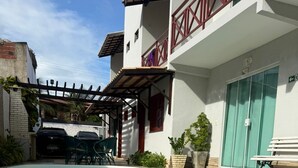 Una piscina con una pérgola, un coche y un edificio con balcón.