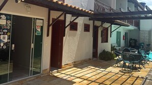 Un edificio con un patio cubierto, piscina y mobiliario exterior.