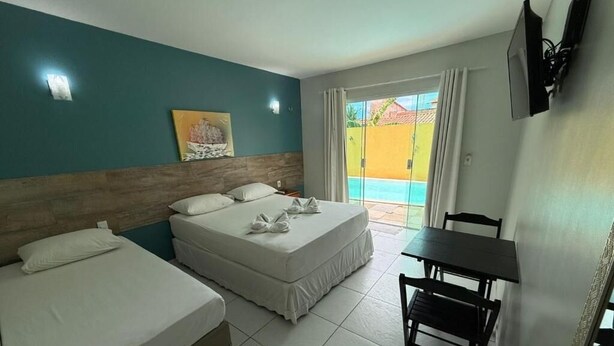 Habitación de hotel con dos camas, una mesa de comedor y vista a una piscina.
