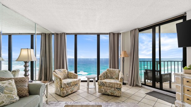 Un balcon spacieux offrant une vue sur l’océan, aménagé avec un canapé, deux fauteuils et une petite table.