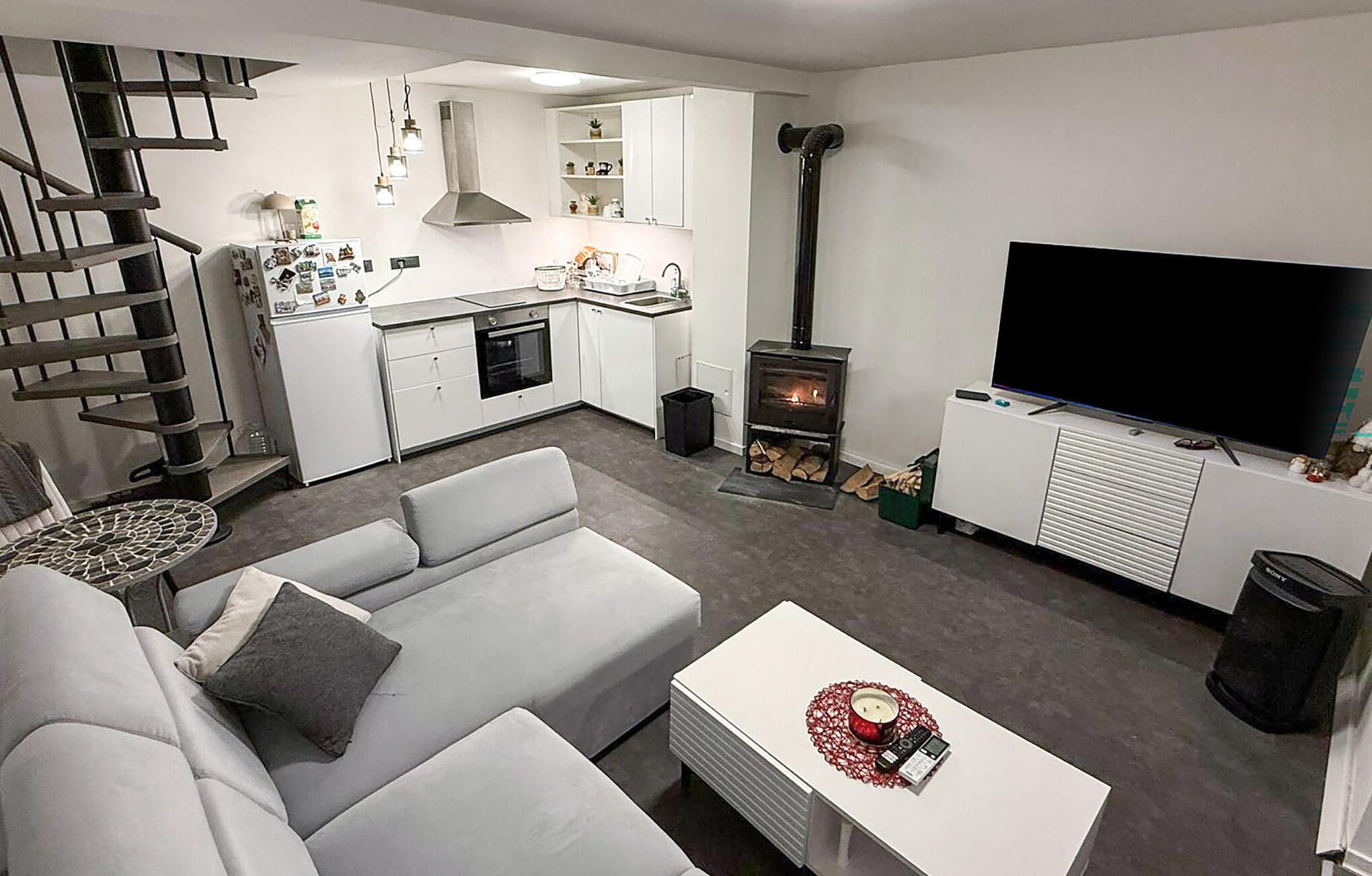 Een moderne woonkamer met een bank, een salontafel, een televisie, een open haard en een keukenhoek.