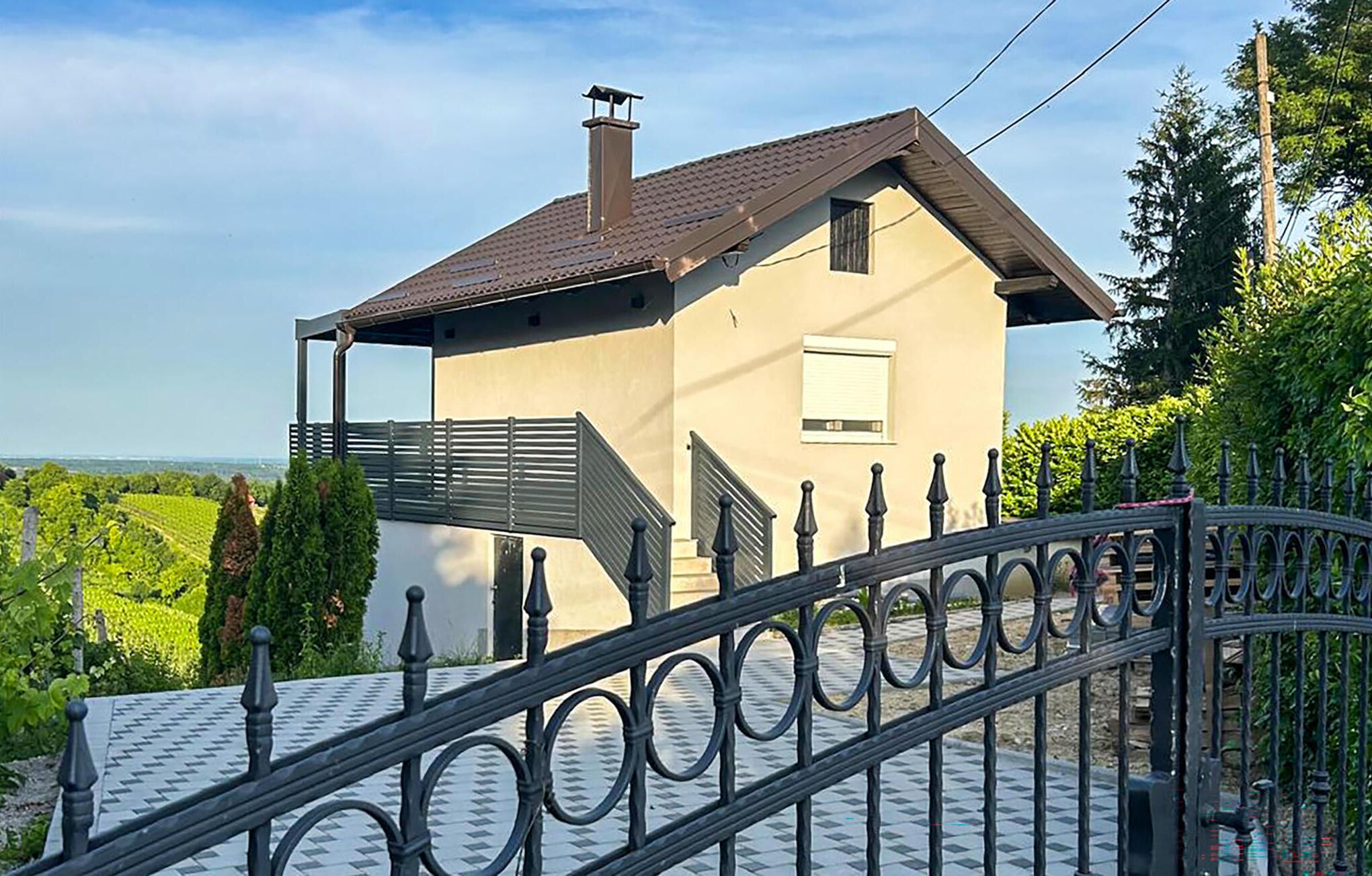 A house with a sloped roof, a chimney, and a gated entrance.