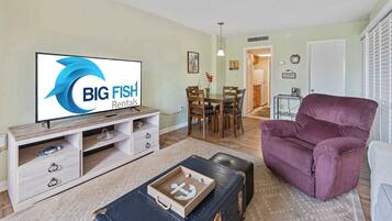 A living room with a television displaying 'BIG FISH Rentals,' a dining area with wooden furniture, and a purple armchair.