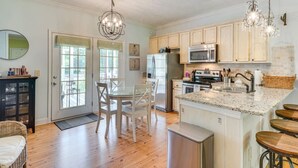 Una cocina con una isla central, un comedor con sillas, un refrigerador, un microondas y un fregadero.